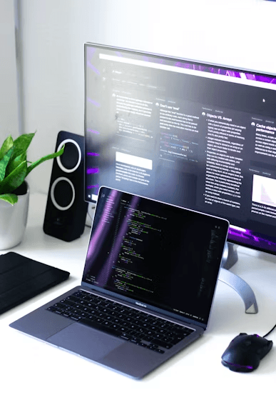 Software development workstation with code displayed on multiple screens